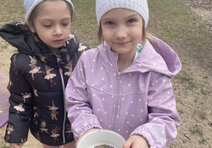 dziewczynki prezentują swoją zupę z piasku