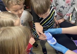 dzieci oglądają proces plombowania zęba na modelu szczęki