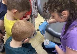 pani stomatolog pokazuje dzieciom jak działa ssak