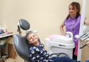 Chłopiec uśmiecha się siedząc na fotelu dentystycznym
