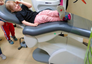Dziewczynka śmieje się siedząc na poruszającym się fotelu dentystycznym