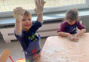 Chłopiec pokazuje do zdjęcia ręce a na nich masa z mąki i wody