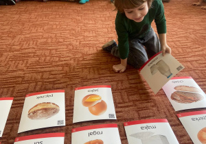 Chłopiec wybiera kartę na dywanie ze wskazanym produktem