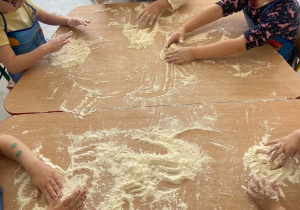 Dzieci wyrabiają ciasto z mąki i wody