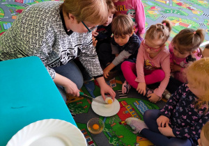 Dzieci obserwują, jak nauczycielka przekrawa ugotowane na twardo jajko
