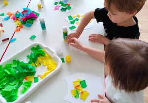 Dzieci ozdabiają szablony sów kolorowymi skrawkami bibuły