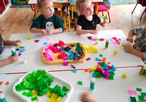 Dzieci wyklejają szablony sów kolorową bibułą