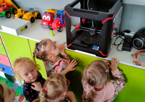 Dzieci przyglądają się procesowi drukowania sowy na drukarce 3D