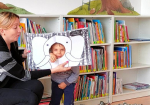 Chłopiec z ręką w dziurze książki. Ręka imituje trąbę słonia przedstawionego na ilustracji