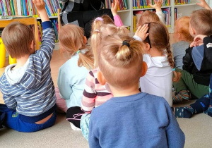 Dzieci podnoszą ręce do góry, by udzielić odpowiedzi na pytanie, co może znajdować się na talerzu w "Książce z dziurą"