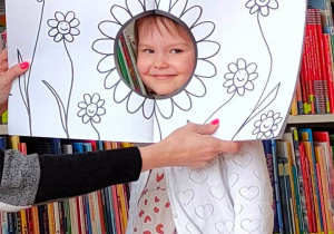 Dziewczynka z głową w dziurze ilustracji przedstawiającej kwiat