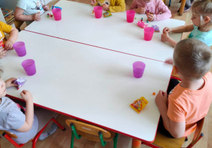 Dzieci przy stolikach jedzą urodzinowe żelki