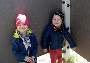 Chłopcy pozują do zdjęcia przy tablicy w ogrodzie przedszkolnym