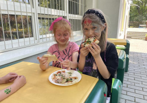 dzieci jedzą przygotowaną przez siebie pizzę