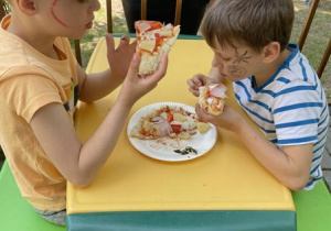 dzieci jedzą przygotowaną przez siebie pizzę