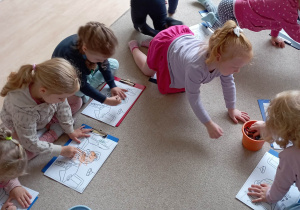 Dzieci kolorują ilustracje przedstawiające kameleona Leona