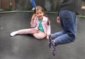 Dziewczynka i chłopcy podczas zabawy na trampolinie