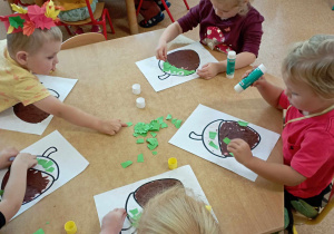 Dzieci podczas wyklejania żołędzi papierem kolorowym