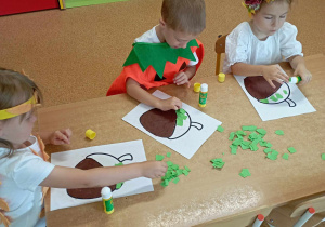 Dzieci wyklejają szablony żołędzi papierem kolorowym