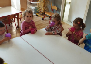 Sala przedszkolna. Dzieci siedzą przy stołach i degustują soki.