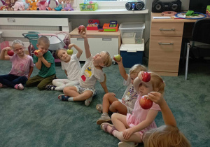 Dzieci pokazują przyniesione do przedszkola jabłka