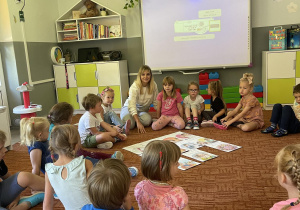 Dzieci na dywanie w kole rozmawiają z nauczycielką