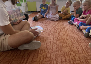 Dzieci na dywanie słuchają czytanej przez Pana opowieści o Myszce Molly