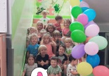 Dzieci siedzą na chodach ozdobionych balonami.