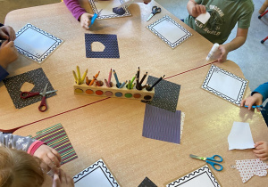 Dzieci przy stole wycianają dowolne kształty z kolorowego papieru