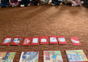 Dzieci na dywanie zapoznają się z ilustracjami dotyczącymi poczty polskiej
