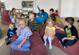 dzieci siedzą na pufach i słuchają opowiadania