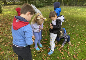 dzieci zbierają kasztany w ogrodzie