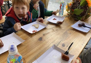 dzieci jedzą pieczone kiełbaski