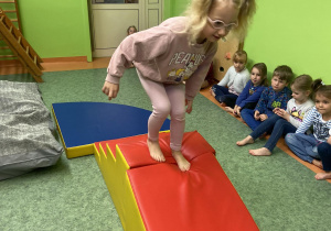 Dziewczynka schodząca po piankowej zjeżdżalni na sali gimnastycznej