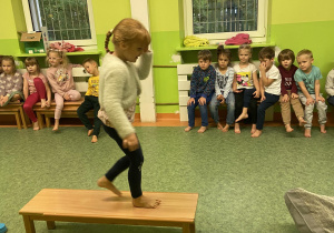 Dziewczynka przechodząca przez ławkę na sali gimnastycznej