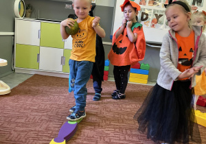 Dzieci przechodzące w sali po równoważni z dynią w ręku