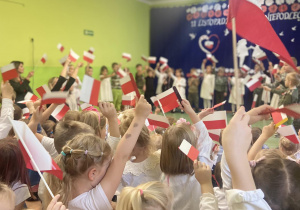 Dzieci trzymające w górze flagi Polski