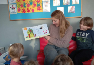 Dzieci przyglądają się ilustracjom w książce czytanej przez jedną z mam