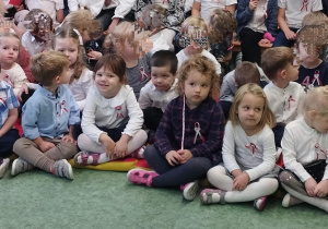 Sala gimnastyczna. Dzieci biorą udział w uroczystości z okazji Święta Niepodległości. Dzieci siedzą na podłodze.