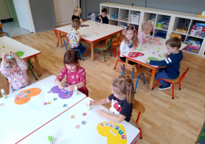 Sala przedszkolna. Sala przedszkolna. Dzieci siedzą przy stoliku i wyszukują wśród obrazków na stole, wskazany przez nauczyciela obrazek, ilustrujący poszczególne prawa dziecka.