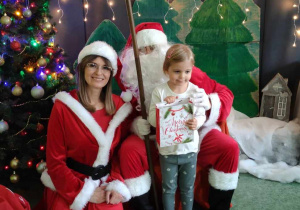 Dziewczynka z Mikołajem i Mikołąjką na tle świątecznej dekoracji