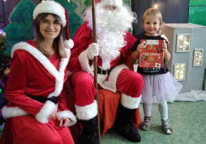 Dziewczynka z Mikołajem i Mikołajką na tle świątecznej dekoracji