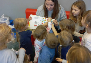 Dzieci wskazują na ilustracji w książce przedmiot wymieniony przez panią czytającą tę książkę