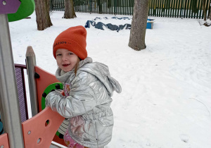 Dziewczynka podczas zabawy w zaśnieżonym ogrodzie przedszkolnym