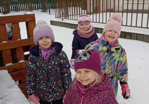 Dziewczynki pozują do zdjęcia w zaśnieżonym ogrodzie przedszkolnym