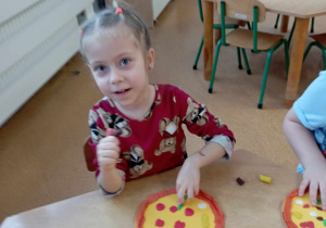 Dziewczynka podczas wykonywania pracy plastycznej przedstawiającej pizzę