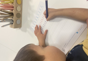 chłopiec pisze litery po śladzie