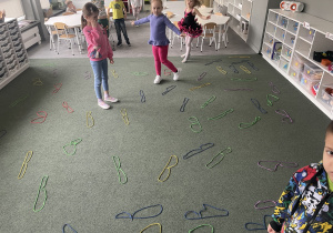 dzieci układają na dywanie wielkie litery B z kolorowych sznurków