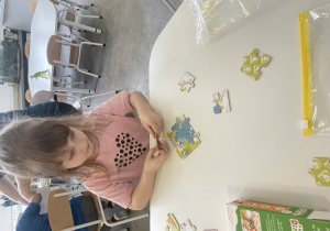 dziewczynka układa puzzle z dinozaurem