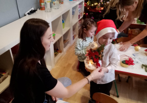 Sala przedszkolna. Dzieci wspólnie z rodzicami przygotowują świąteczny stroik.